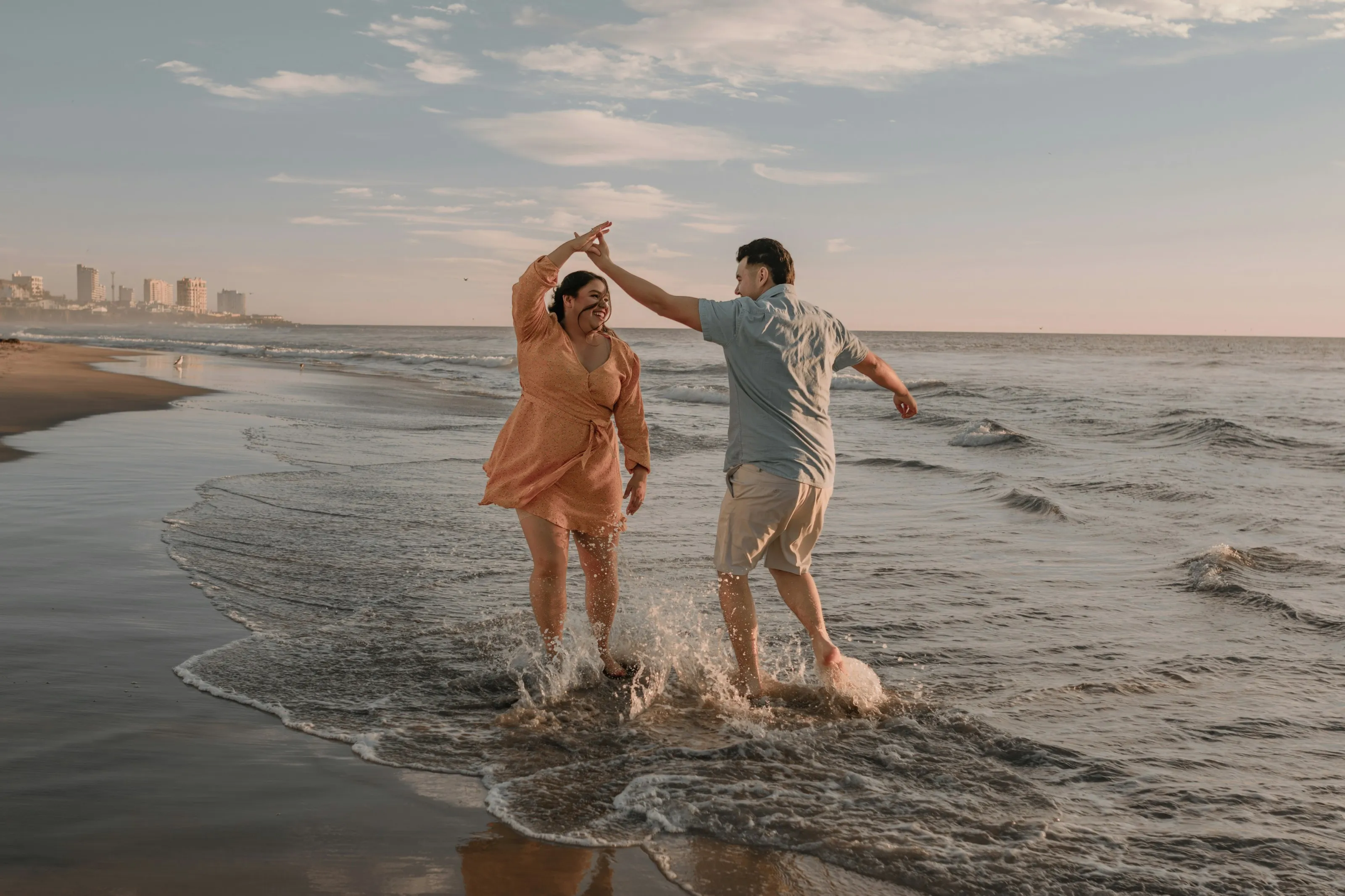 A couple laughing as they splash through the shallows at the beach