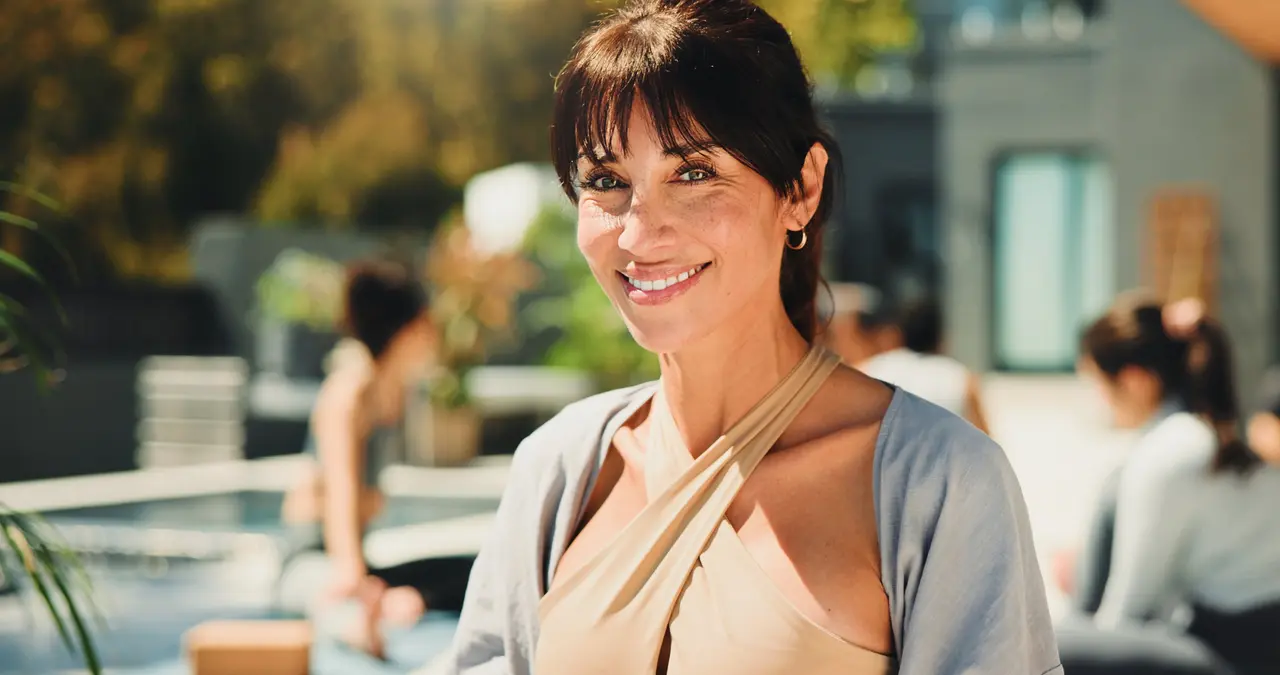 A smiling woman in yoga wear at an outdoor class