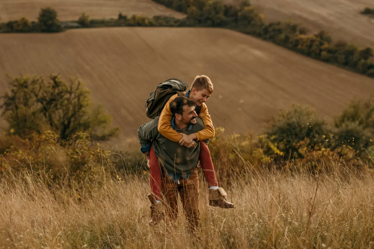 A father giving his son a piggyback through a golden field