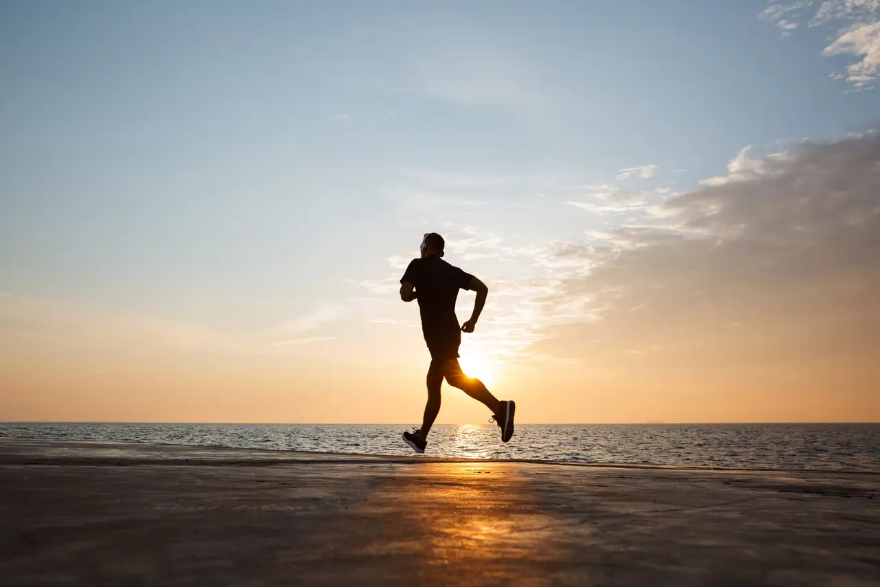 A man running along the shoreline at sunrise